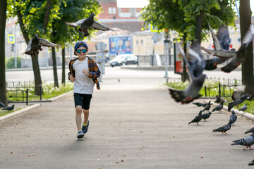 Fototapeta premium Boy playing with pigeons. A child in sunglasses on a walk