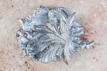 Old aluminum leaf ashtray on concrete background.