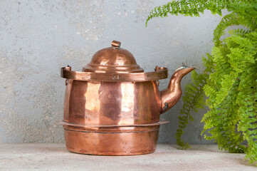 Old copper kettle on concrete background.