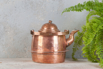 Old copper kettle on concrete background.