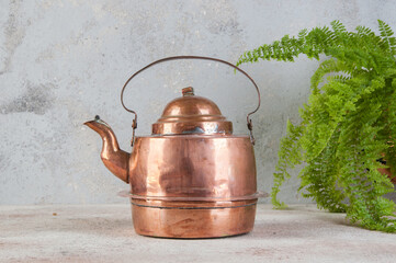 Old copper kettle on concrete background.