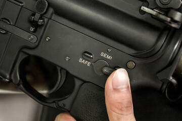 Finger selecting Rifle gun selective switch on safe mode position