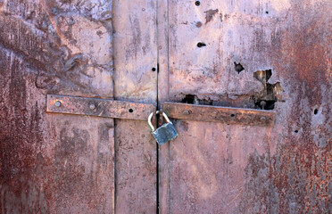 Metal lock on a metal old rusty door with corrosion, damaged and defects