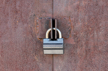 Old rusty metal door with corrosion and defects closed with a metal lock