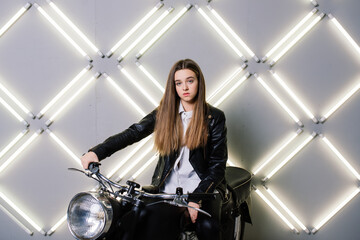 Fototapeta na wymiar Young fashion girl posing in black leather with motorcycle.
