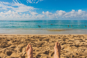 View of mans feet on sandy beach overlooking beautiful ocean horizon 