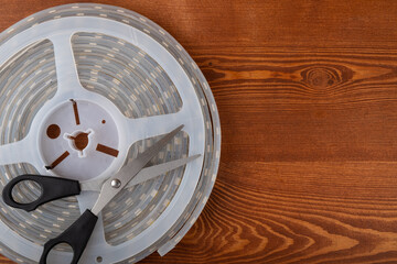 led strip with scissors on wooden background with copy space