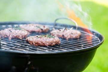 Meat Burgers Grilled on Fire Flames Charcoal Grill in Garden at Summer