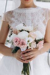 The bride is holding a bouquet of white roses. Beautiful wedding bouquet. Morning of the bride.