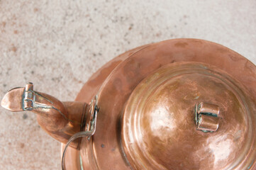 Old copper kettle on concrete background.
