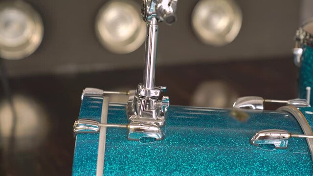 Caucasian male sets the blue drum to the drum-set to start the rehearsal
