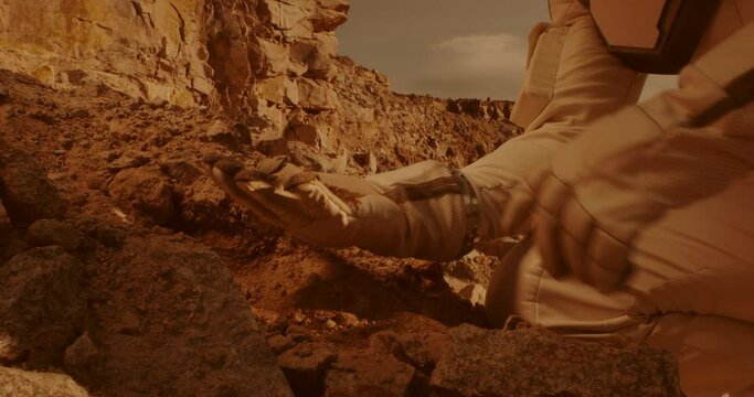 Unrecognizable cosmonaut examining soil on Mars