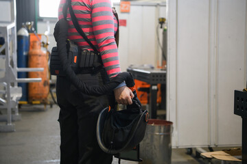 a portrait of a women welder holding a helmet and preparing for a working day in the metal industry