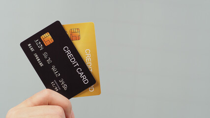 Hand is holding two credit card in black and gold color isolated on grey background.