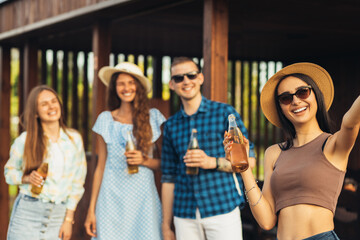 young friends making barbecue and drinking drinks, preparing meat in nature, having fun and taking selfie , youth lifestyle