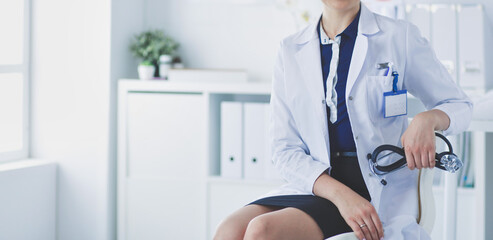 Portrait of young female doctor sitting at desk in hospital