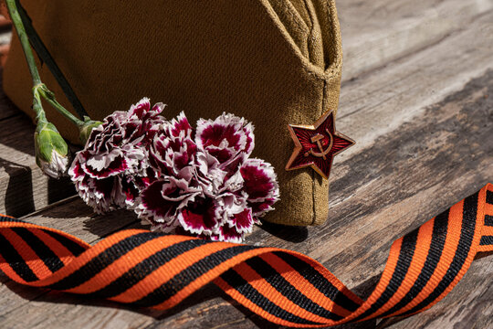 Military concept May 9, military cap with St. George ribbon, Order of the Great Patriotic War, 2nd degree on a wooden background with flowers, filmed in Russia, Yekaterinburg 10.06.2021