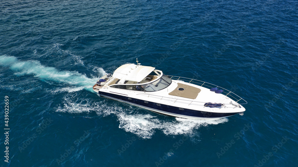 Poster aerial drone photo of small luxury yacht cruising in deep blue sea near aegean island, greece