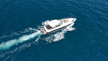 Aerial drone photo of small luxury yacht cruising in deep blue sea near Aegean island, Greece