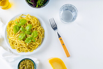 Spaghetti with pesto sauce and basil on a white background. Pasta with sauce pesto and ingredients. Traditional Italian cuisine. Food styling