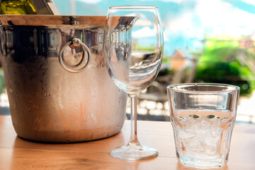 White wine cold in glass with ice, steel silver bucket in hot summer day in beach restaurant or cafe, succulent plant in pot on table