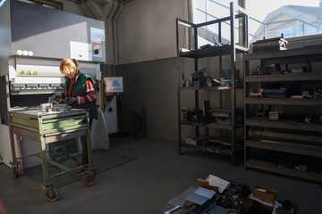 woman working in a modern factory and preparing materia for a CNC machine. 