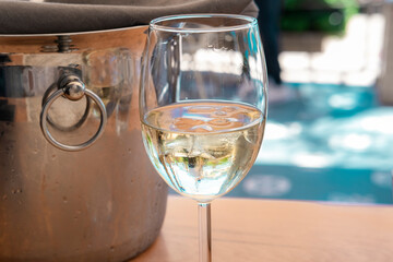 White wine cold in glass with ice, steel silver bucket in hot summer day in beach restaurant or cafe, succulent plant in pot on table
