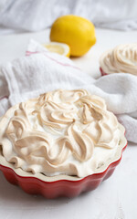 Lemon Merinque Tartlette in a red mini pie form, a dish towel and a lemon