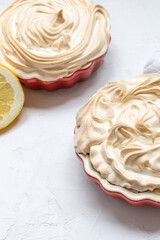 Two Lemon Merinque Tartlettes in red mini pie forms.