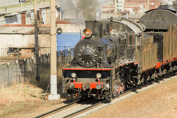 retro steam locomotive rides on the railroad releasing clouds of smoke