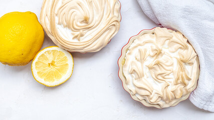 Two Lemon Merinque Tartlettes in red mini pie forms.