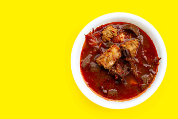Northern Thai Pork Curry in bowl on yellow background.