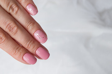 Beautiful soft pink varnish and sparkles on nails - gel varnish salon coating manicure.