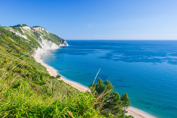 Fototapeta premium The beach of Mezzavalle view from above unique bay in Conero natural park dramatic coast headland rock cliff adriatic sea Italy turquoise transparent water