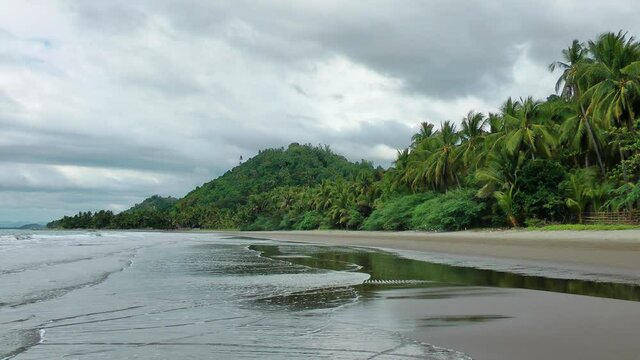 Sand beach with mountain background under cloudy sky, Philippines