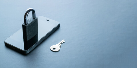 Mobile security. Modern space grey mobile phone with padlock, key on dark background. Identity...