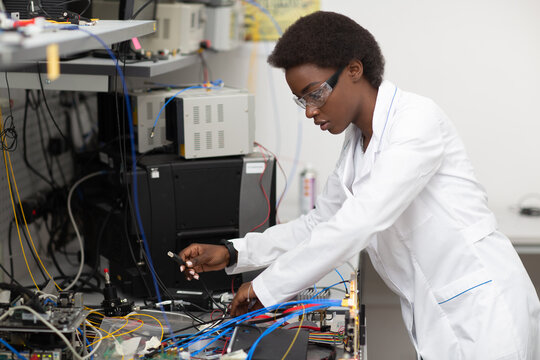 Scientist african american woman working in laboratory with electronic tech fiber optic encryption device. Research and development of electronic devices by color black woman.
