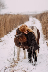 A two-colored pony and a child walk through a snow field 3092.