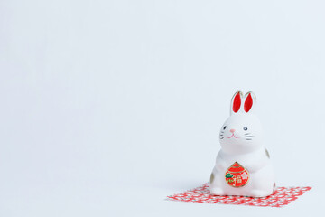 干支の卯年、白を背景に干支の横を向き赤い敷物に座るウサギ