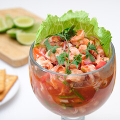 Cóctel de camarones en ceviche con bebida, limon y galletas saladas.