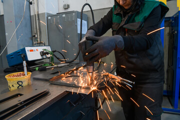 a woman working in the modern metal production and processing industry welding the product and prepares it for a cnc machine
