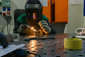 Professional welder performs work with metal parts in factory, sparks and electricity. Industry worker banner.