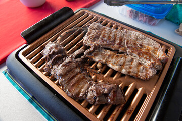 Close up beef meat or filet on the electric grill as part of a backyard barbecue or carne asada for a family reunion dinner or meal