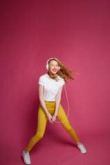 Attractive blonde woman in a white headphones on a pink background