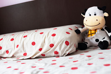 Close-up: a children's room, a bed with a pillow, next to a soft toy cow.