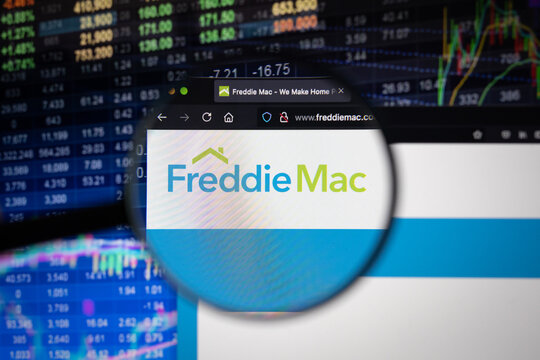 Freddie Mac company logo on a website with blurry stock market developments in the background, seen on a computer screen through a magnifying glass