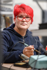 Industrial worker woman soldering cables of manufacturing equipment in a factory