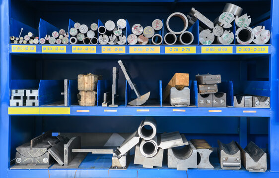 pipes, metal pieces and various metal parts for a CNC machine standing on a shelf