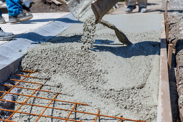 Fresh concrete comes from the concrete mixer, workers make a pedestrian pavement. - 439038008