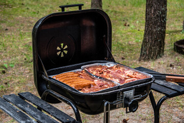 Grilled meat sausage, pork neck, steck - fire, smoke, briquette. Black grill on the recreational land.